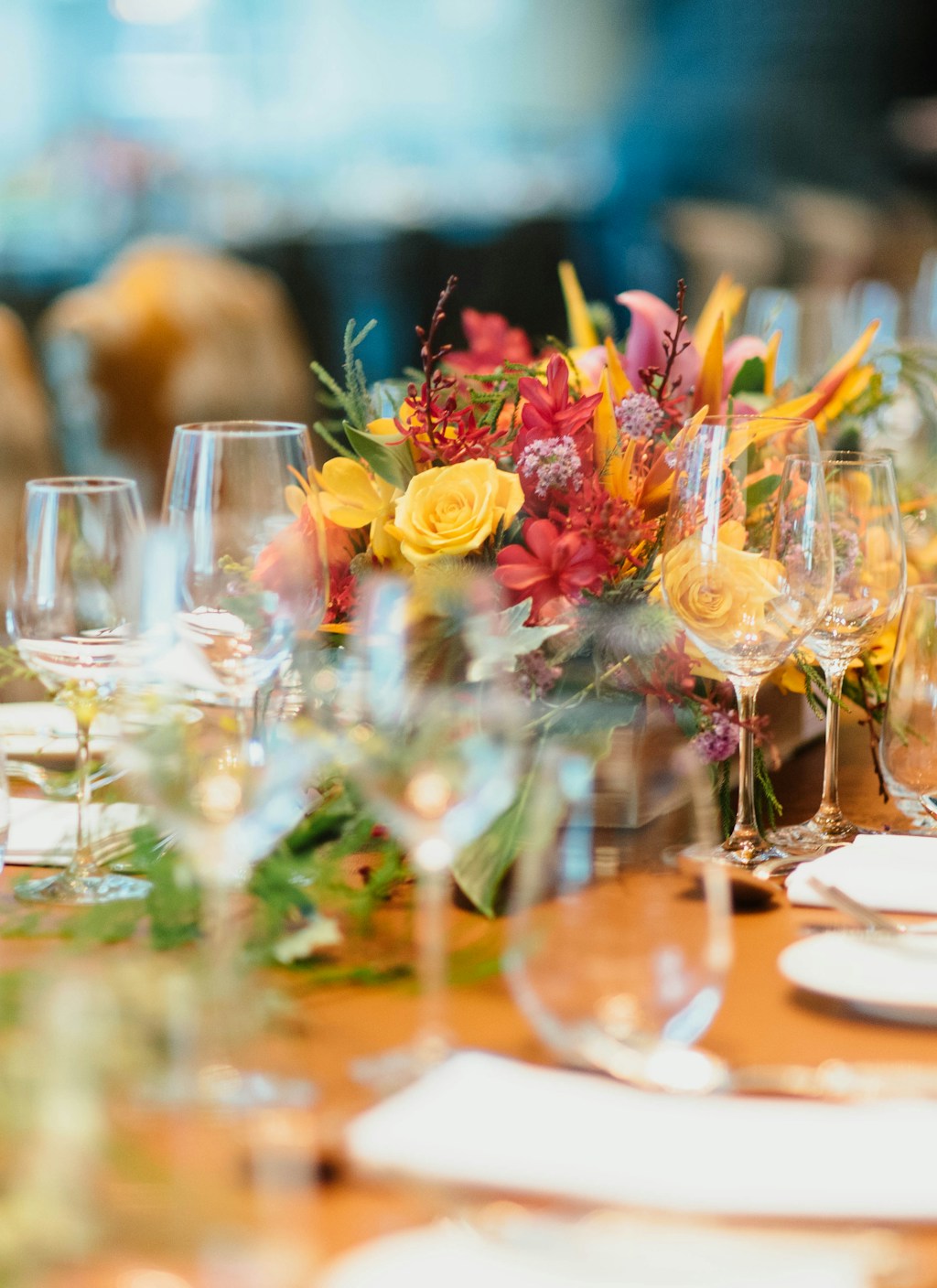 Candlelit banquet table set with wine glasses and a bright floral centrepiece